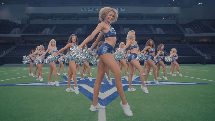 A still image of dallas cheerleaders on the field lined up.