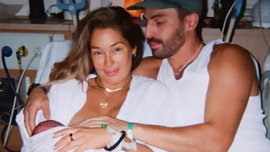 A man and a woman on a hospital bed smiling holding their newborn son.