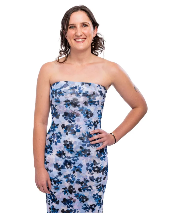 A woman wearing a strapless floral dress standing with her hand on her hip
