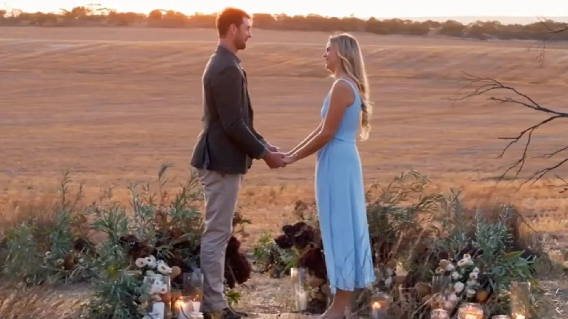 A man and a woman holding hands in a field.