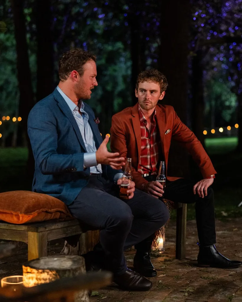 Two men talking around a campfire.