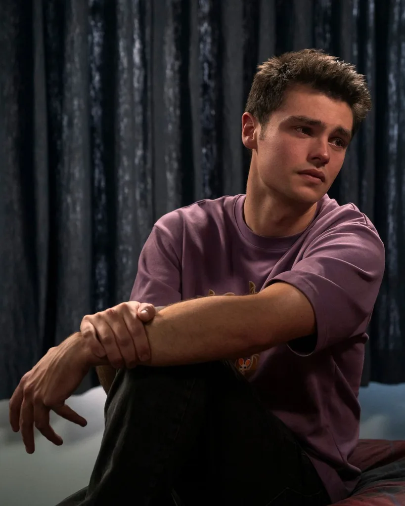 A man wearing a purple t shirt looking sad.