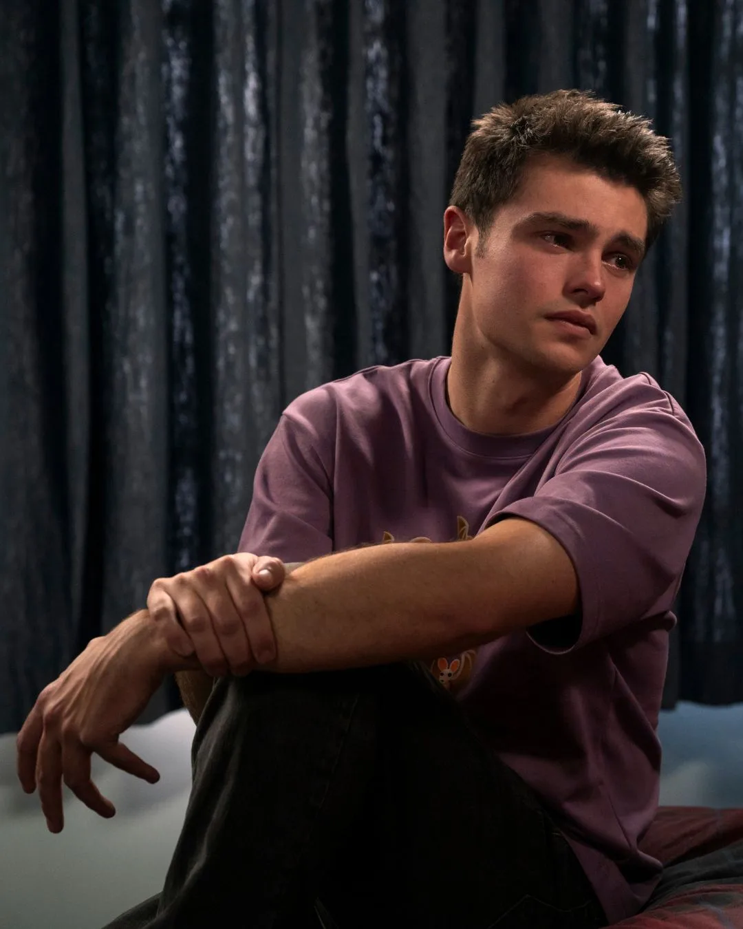 A man wearing a purple t shirt looking sad.