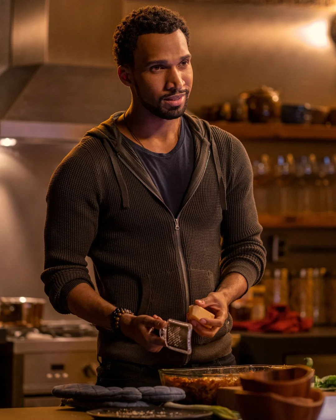A man wearing a brown zip up jumper cooking.