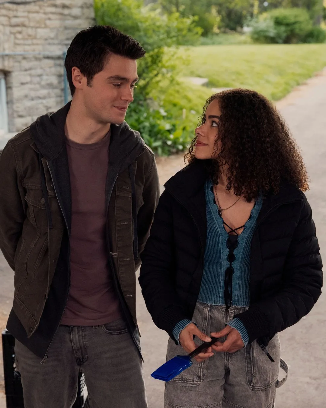 A young man and young woman standing looking at each other. 