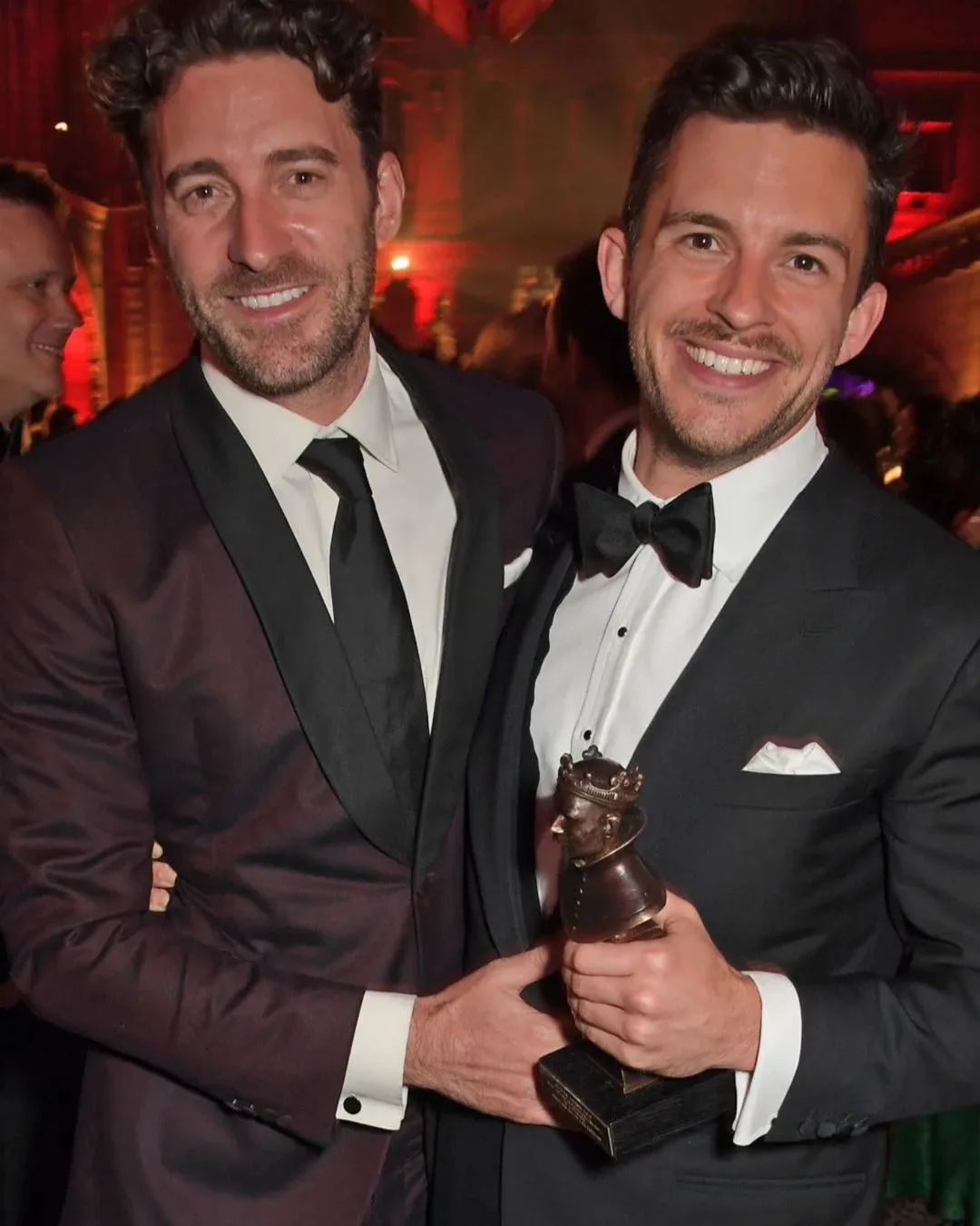 Two men in suits smiling 