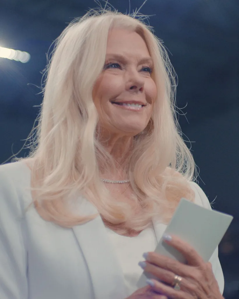 A blonde woman smiling and holding a card.