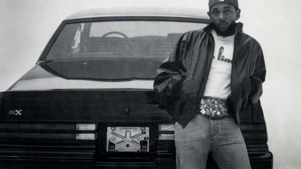 A black and white photo of a man standing in front of a car.