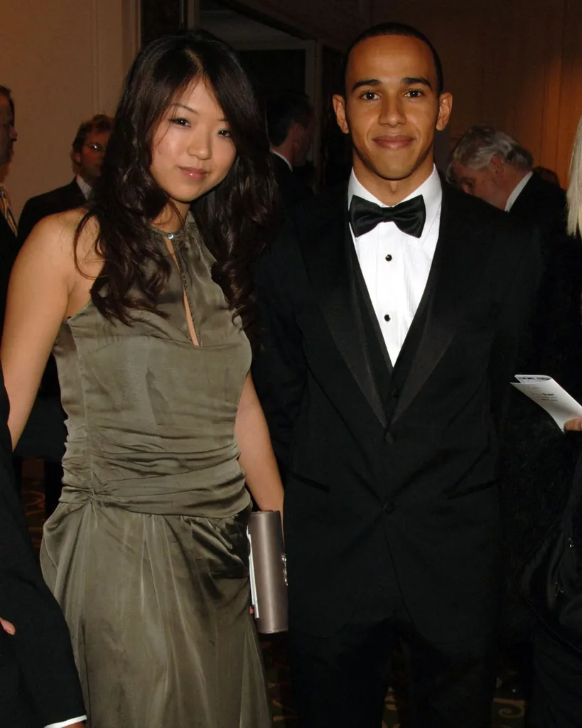 A man wearing a tuxedo smiling next to a woman with long brunette hair and a green silk dress.