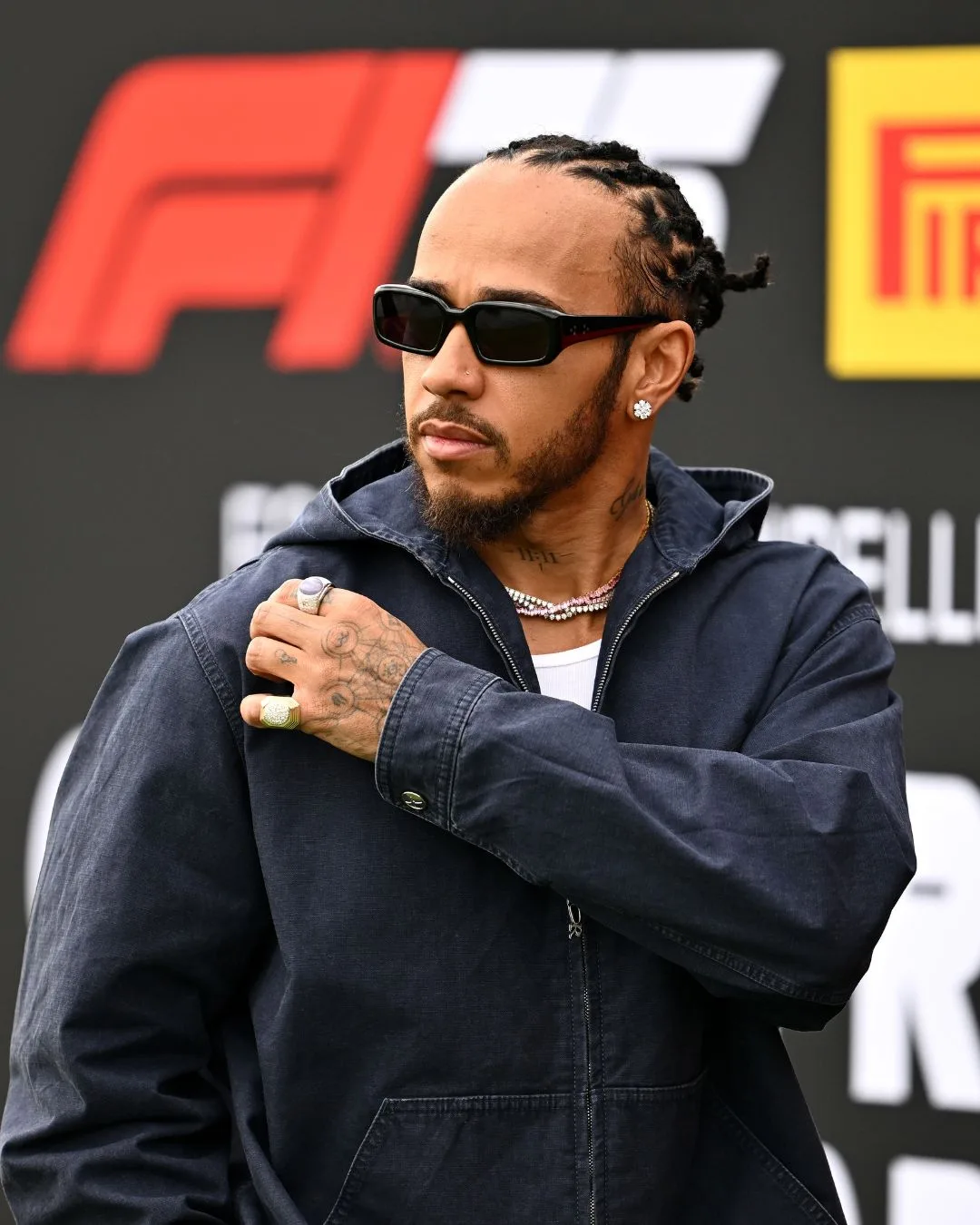 Lewis hamilton wearing sunglasses walking into the F1 paddock before a race. 