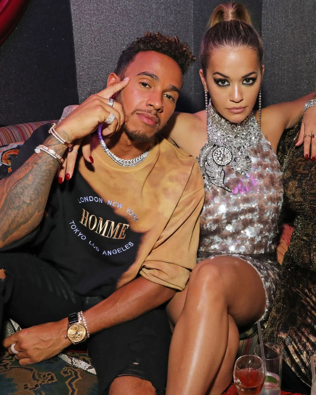 A man and woman staring into the camera dressed in club attire. 