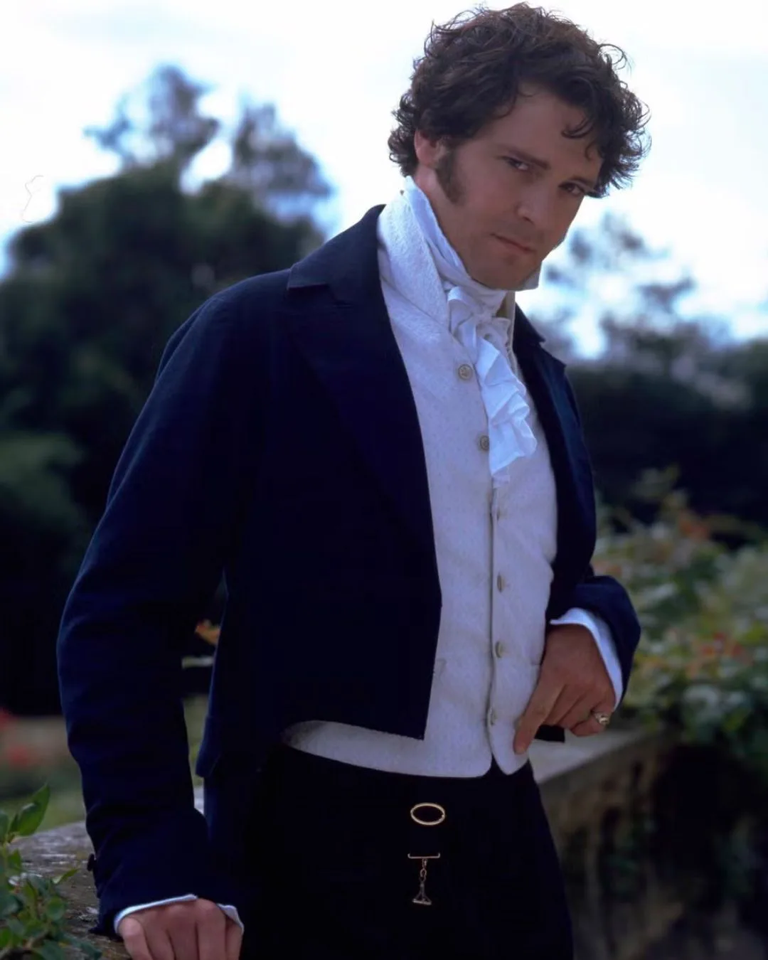 A man wearing a period-style black suit with white vest and an ascot.