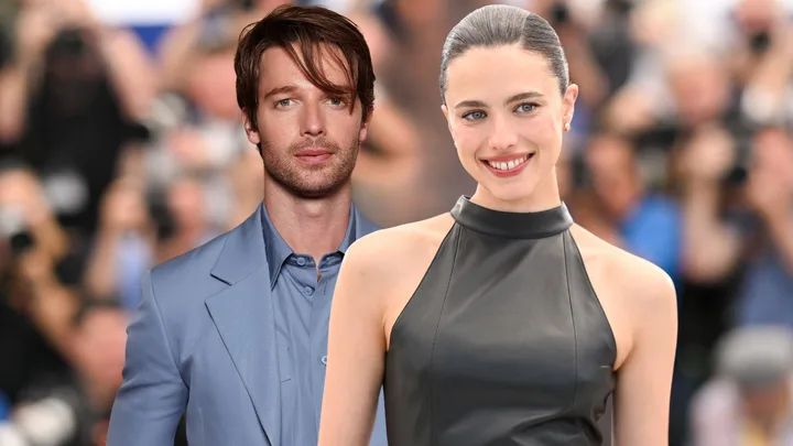 A man dressed in a blue suit and a woman wearing a black halterneck dress, smiling.