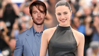 A man dressed in a blue suit and a woman wearing a black halterneck dress, smiling.
