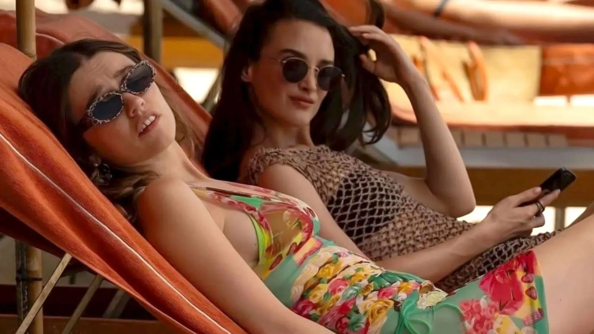 Two women looking concerned while lounging near a pool.