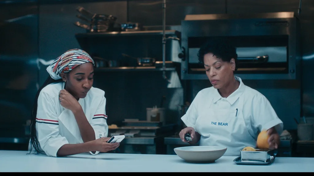 Two woman wearing chefs whites standing in a kitchen.