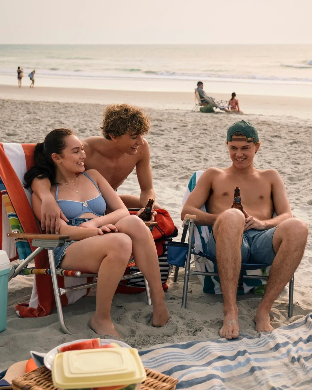 Two young men and one young woman relaxing at the beach. 
