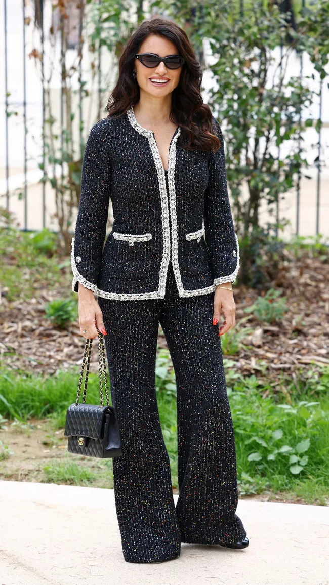 A brunette woman wearing a black and white suit.