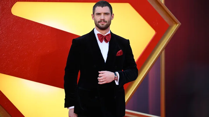 A man wearing a black suit with red bow tie.