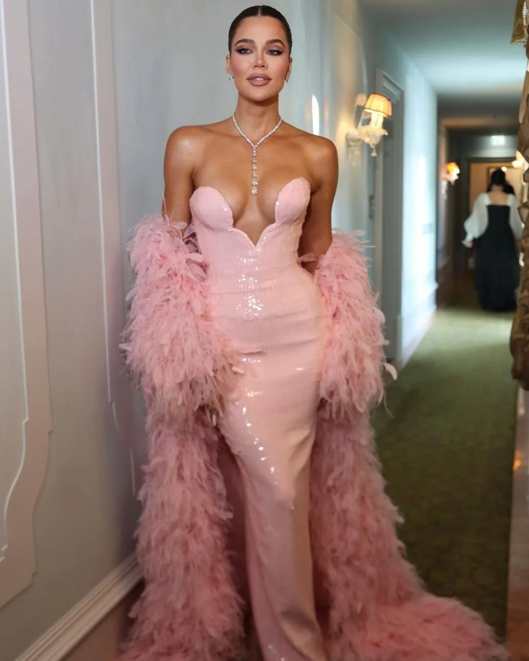 khloe kardashian in a light pink gown and feather train