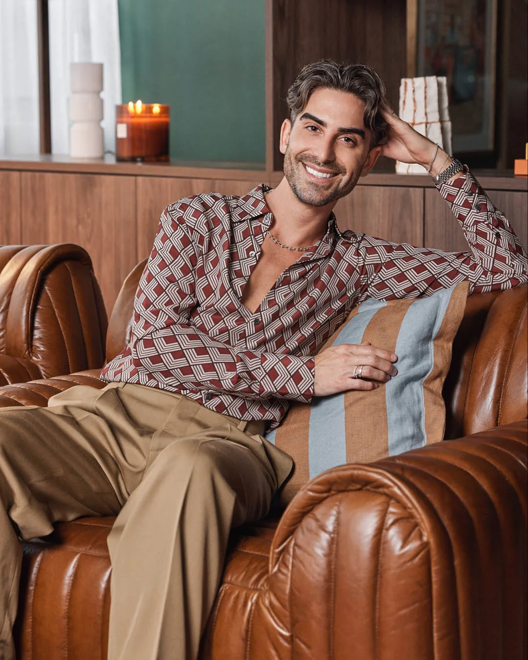 A man sitting on a leather sofa smiling. 