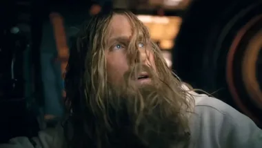 A man with long blonde hair and a dishevelled bead looking confused.