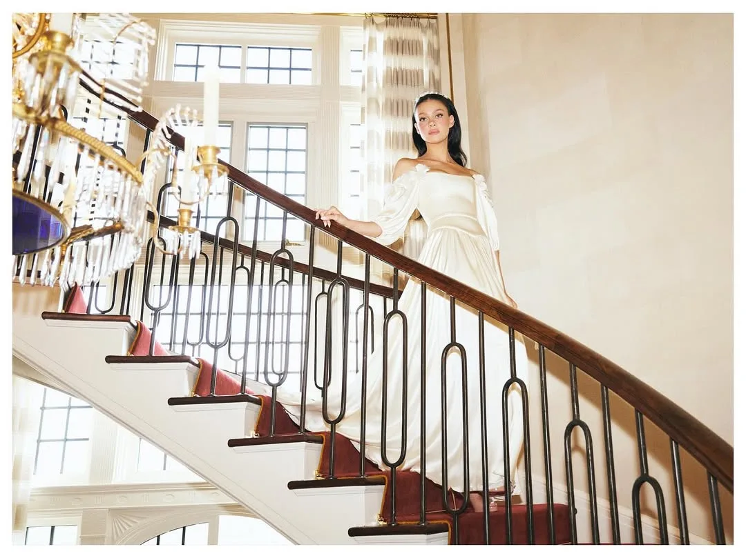 nicola peltz beckham poses on a grand staircase in her second wedding dress 