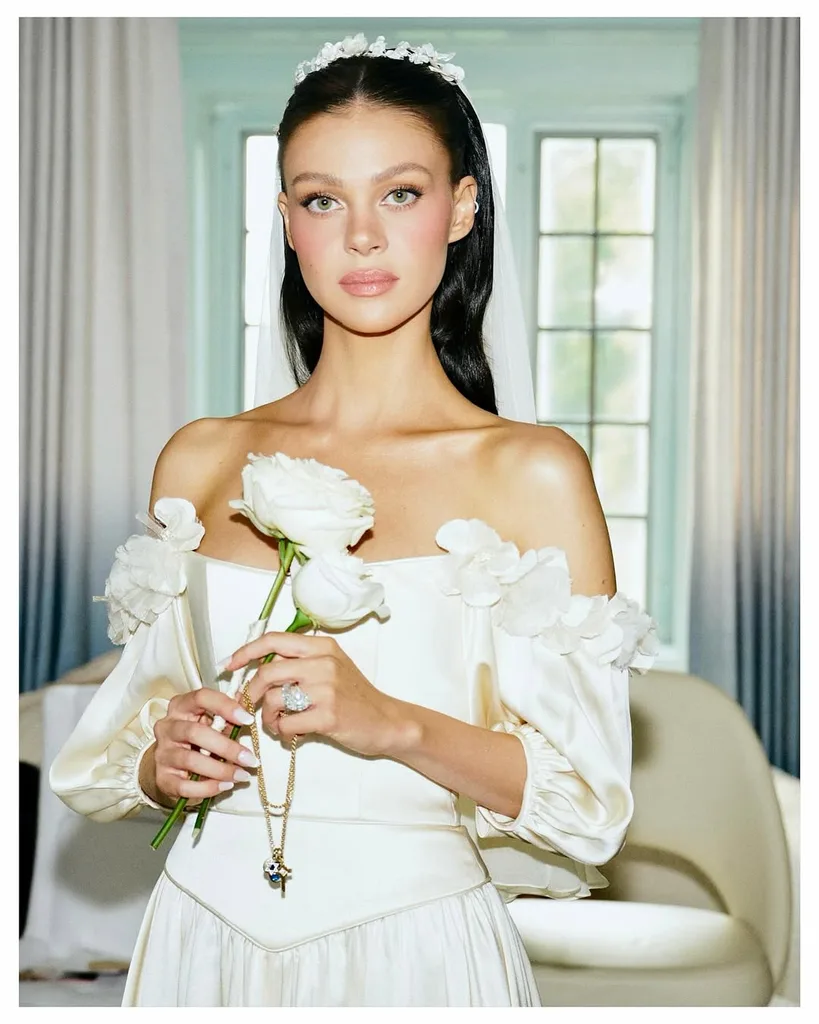 nicola peltz beckham poses with a white rose in her wedding dress at her second wedding to brooklyn beckham