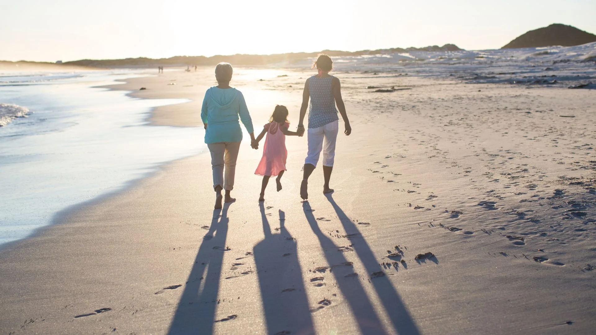 three generations of women walking along the beach