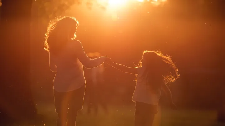 Grandma and granddaughter at sunset holding hands