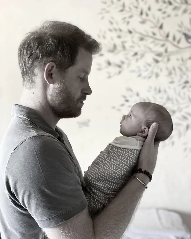 Prince harry holding and staring at baby lilibet