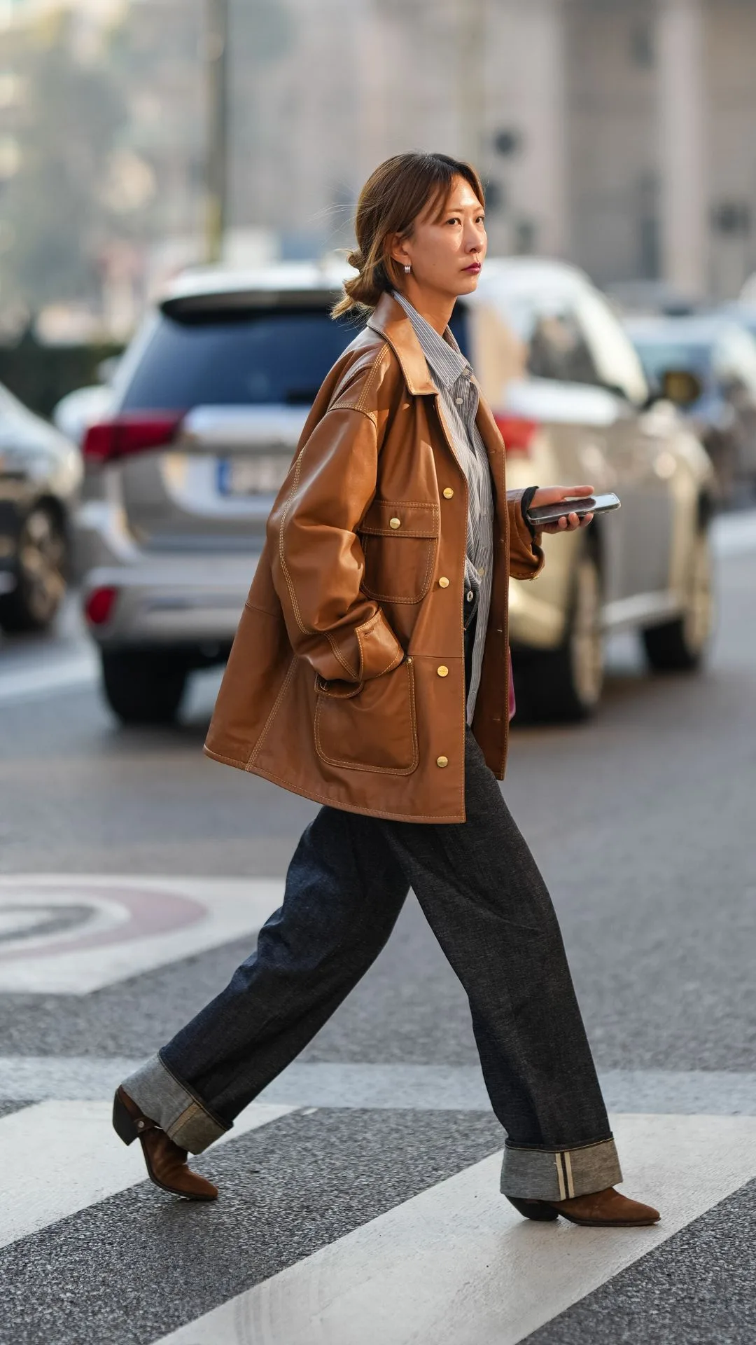 woman wears indigo cuffed jeans brown ankle boots and tan leather jacket