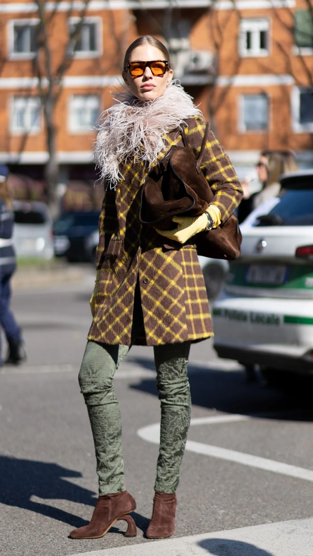 woman wears brown ankle boots skinny jeans and fur trim yellow and brown coat