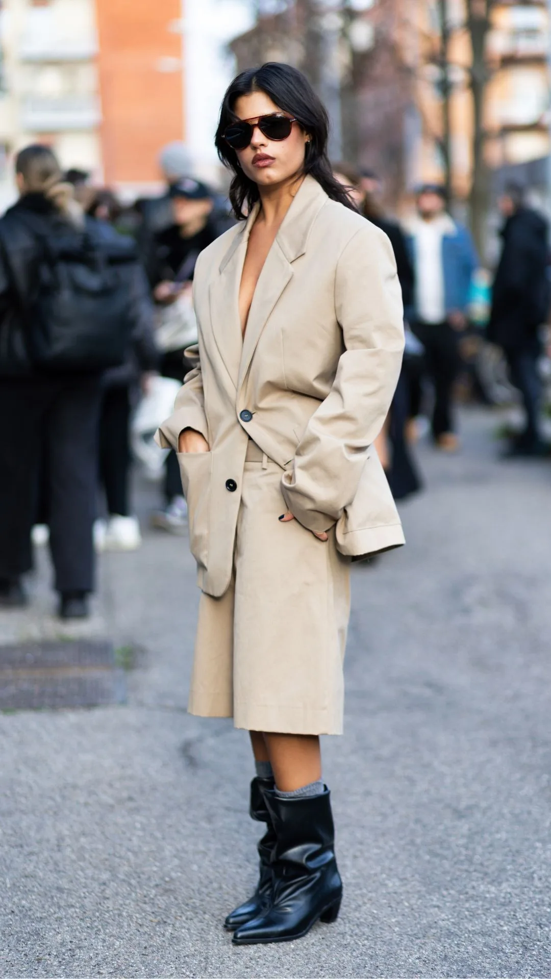 woman wears black slouchy ankle boots with cream shorts and blazer