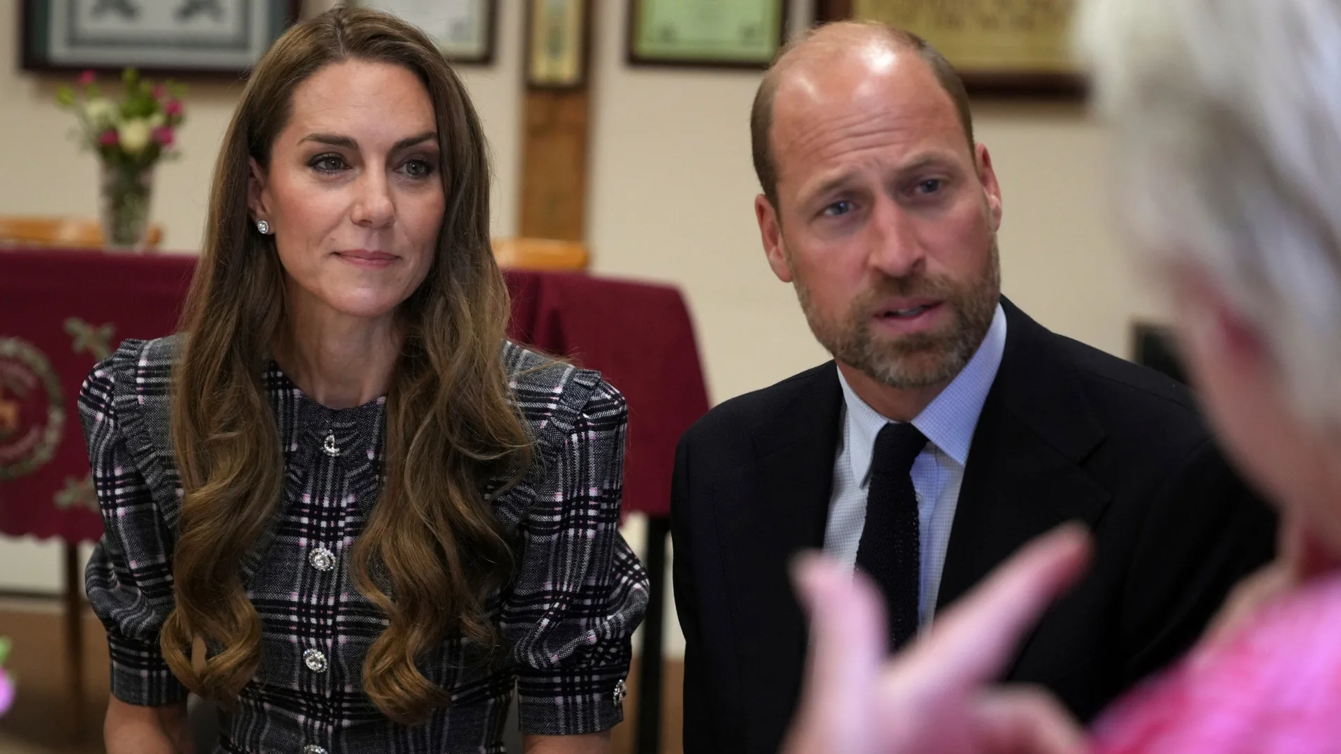 Kate Middleton as seen with William at a royal function in plaid attire and her signature long brown hair. 