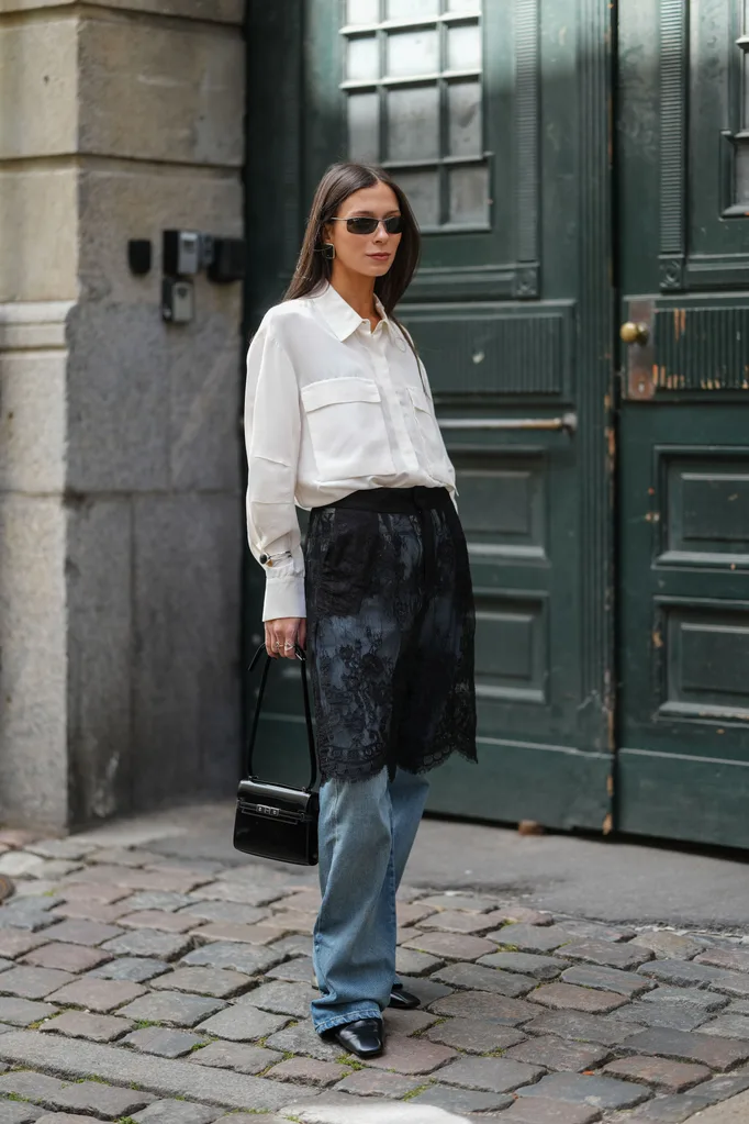 girl wears a sheer lace skirt over jeans and a button down top