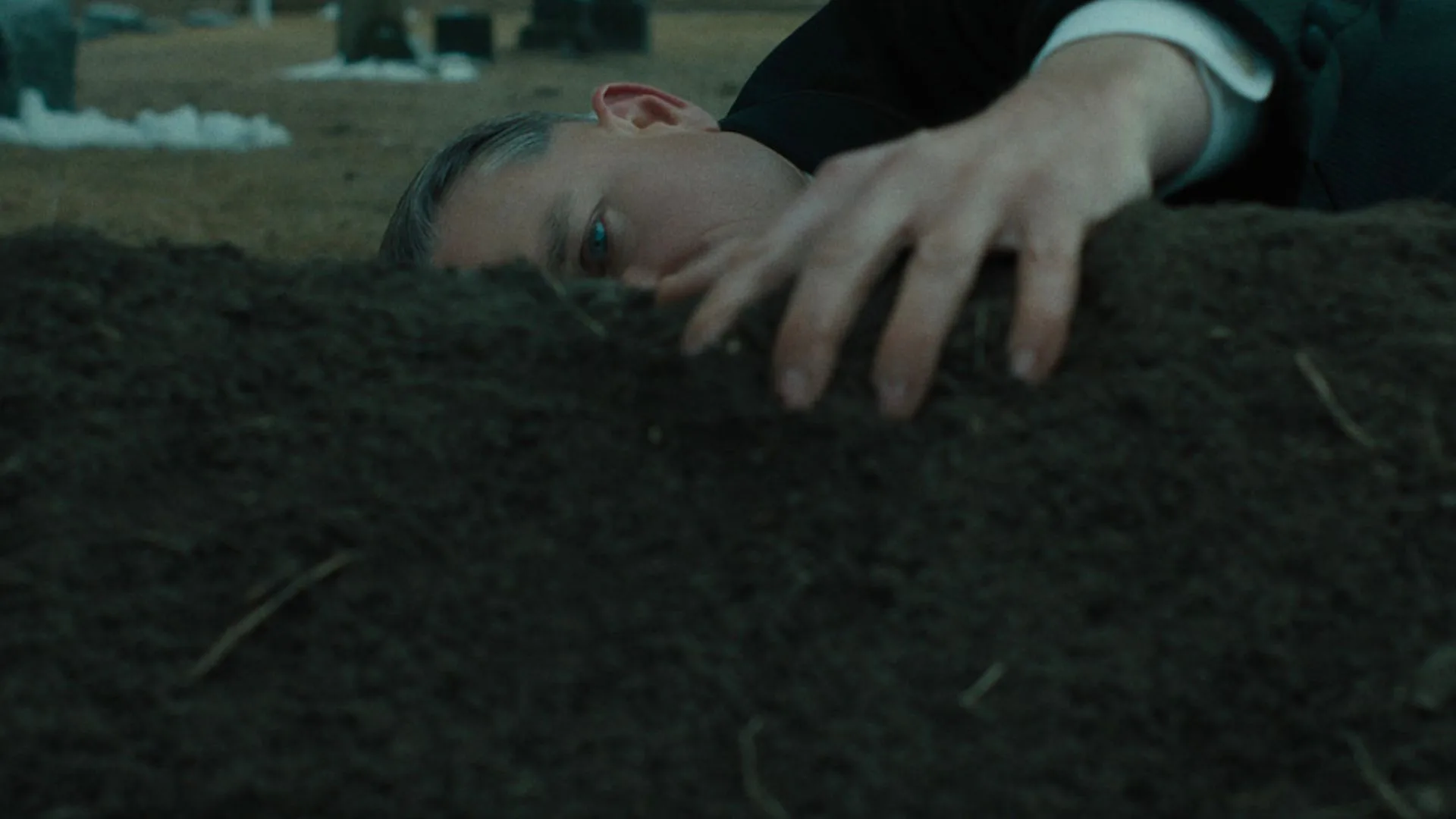 charlie hunnam caresses a grave as ed gein in netflix series monster: story of ed gein