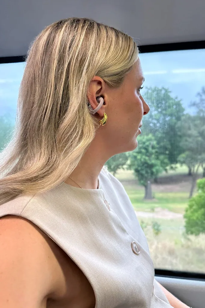 Wearing Shokz OpenDots One Earbuds in pink