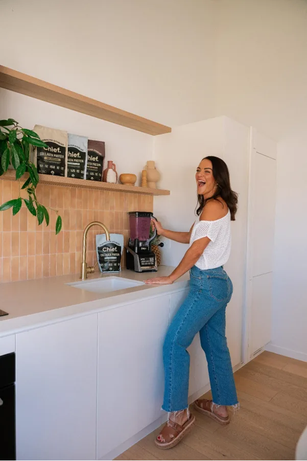 woman laughing in kitchen making wellness smoothie
