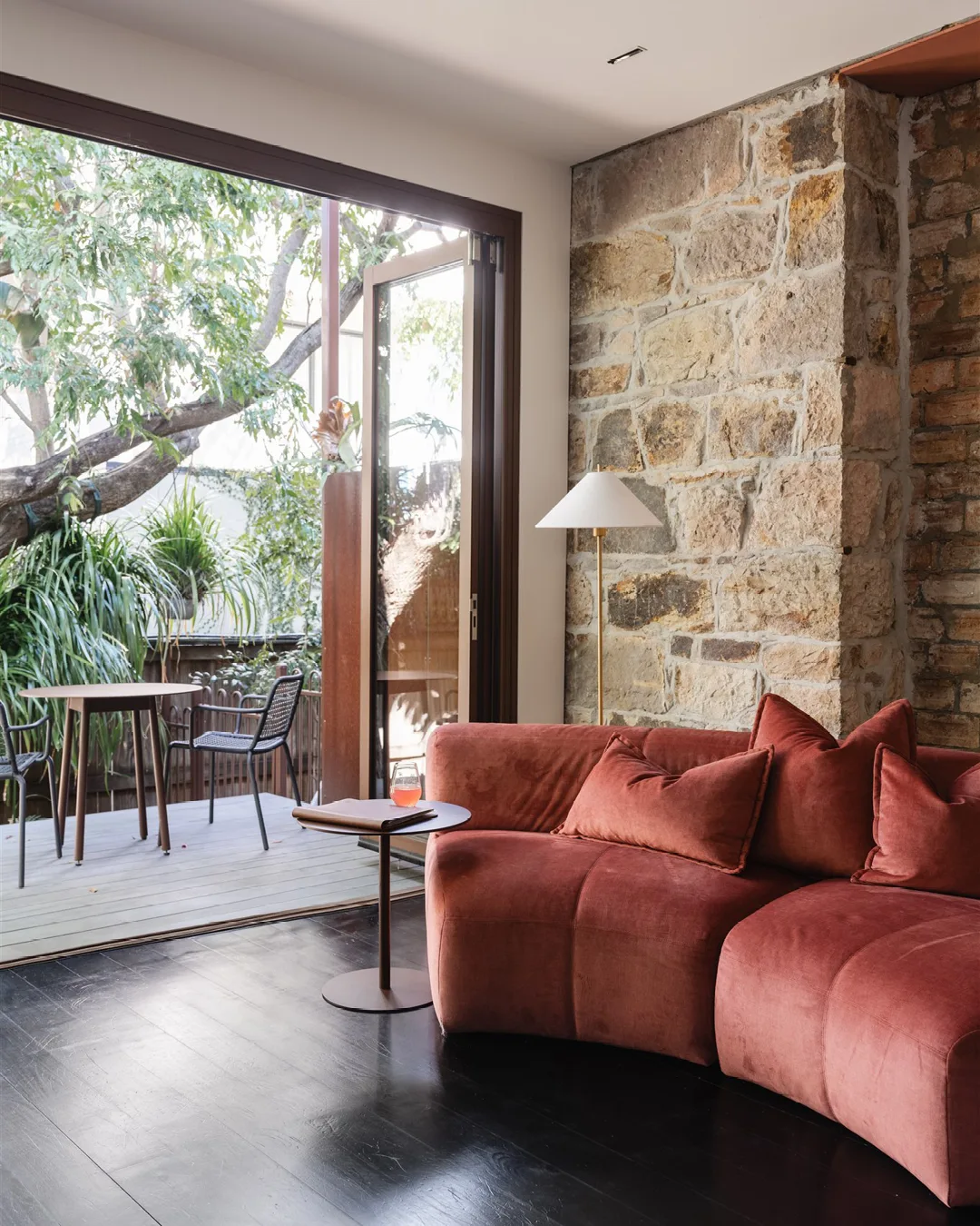 Miss Midgeys Principals Office living space. Pink velvet sofa against exposed sandstone wall.