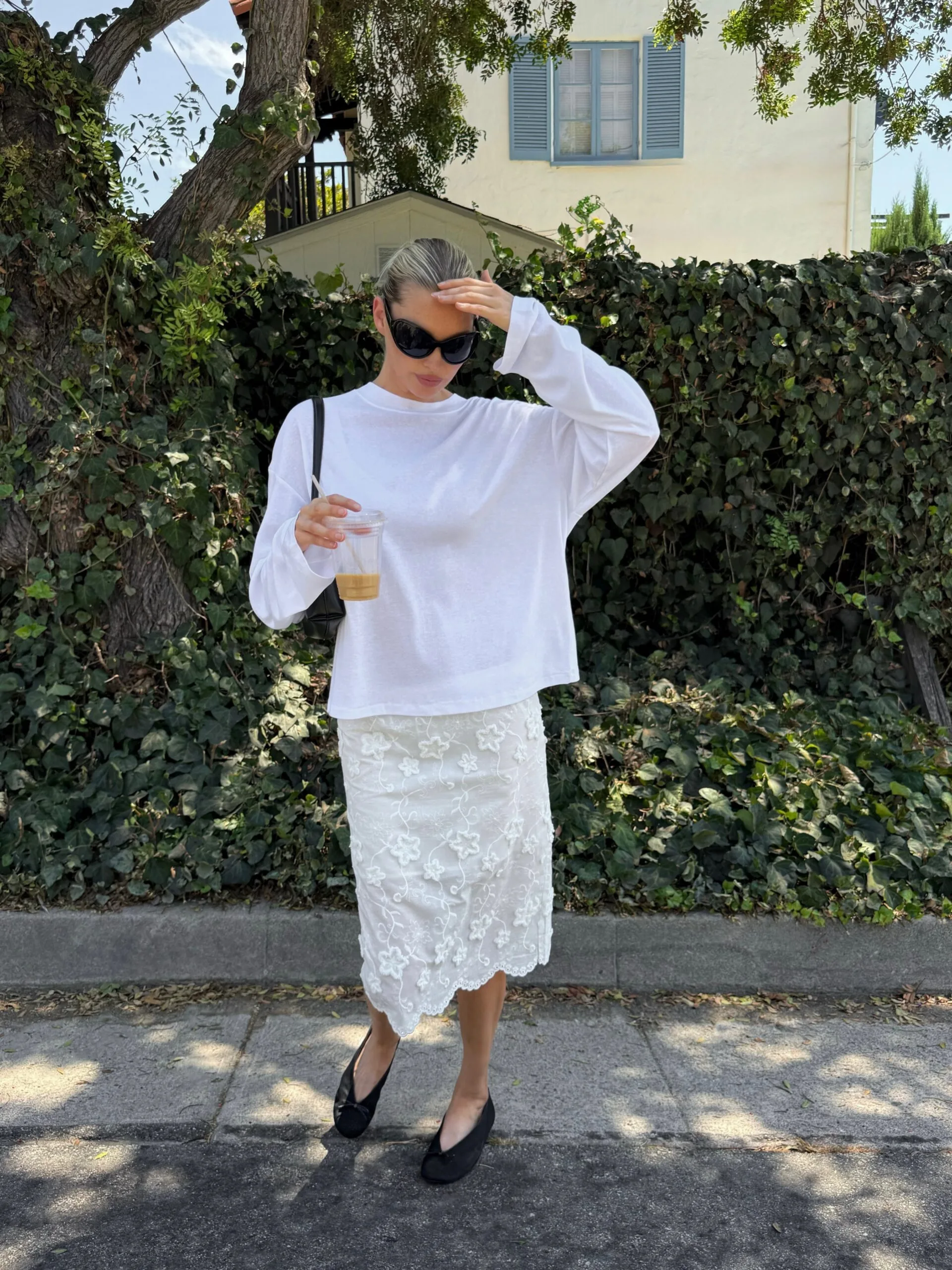 Elsa Hosk wearing a basic white long sleeve top over a sheer beaded white skirt and black ballet flats