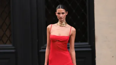 Woman wears red wedding guest dress and gold choker necklace