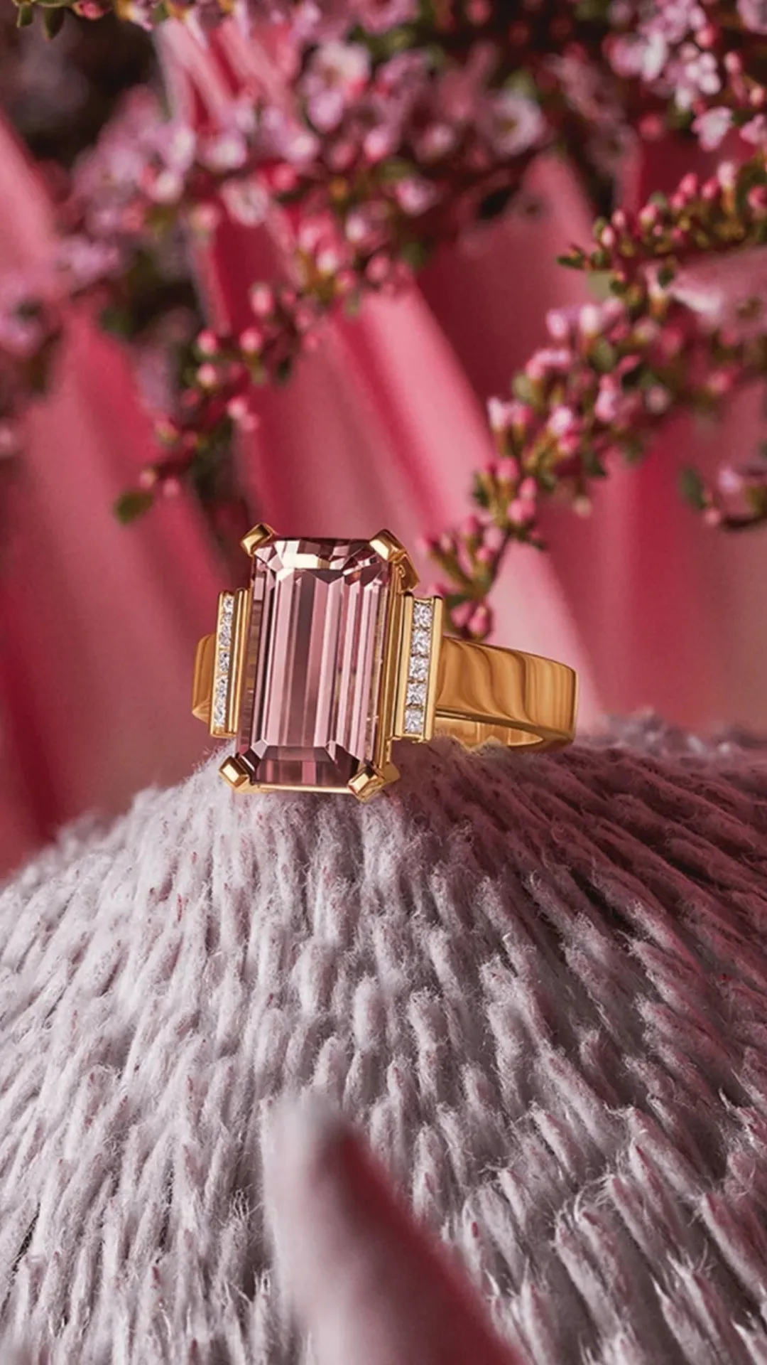 A pink tourmaline and gold ring on a pink background.