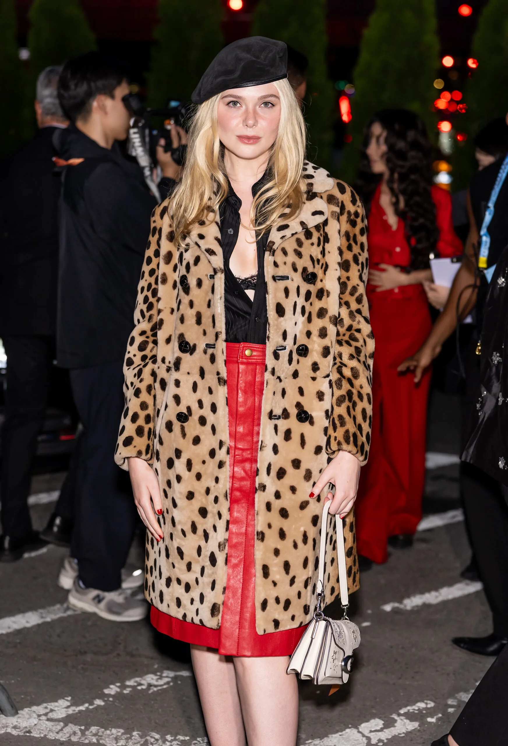 Actress Elle Fanning wears a red skirt, black blouse, leopard print coat and black beret while carrying a white Coach Tabby Bag.