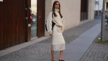 Woman wearing a midi skirt and thong heels with a whiter bomber jacket for summer