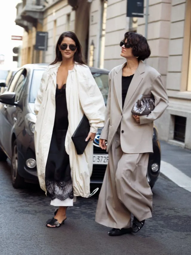 Two women wearing summer jackets and blazers in light stone and white tones at fashion week