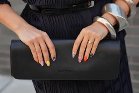 NEW YORK, NEW YORK - SEPTEMBER 11: Samia Laaboudi wears stacked silver large cuff bracelets and a ring, a structured black leather clutch with a flap, a navy ribbed knit shirt dress with a collar and V-neck with elbow-length rolled sleeves and a geometric rib pattern, cinched with a wide black leather belt with a silver square buckle over a matching self-tie, outside Lafayette 148, during New York Fashion Week, on September 11, 2025 in New York, New York (Photo by Edward Berthelot/Getty Images)
