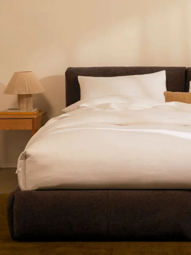 Chocolate brown upholstered Delve bed frame by Eva covered in off-white linen bedding