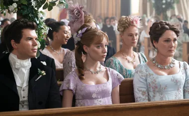 Guests at a wedding in Regency era attire in a scene from "Bridgerton," sitting in a church with floral decorations.