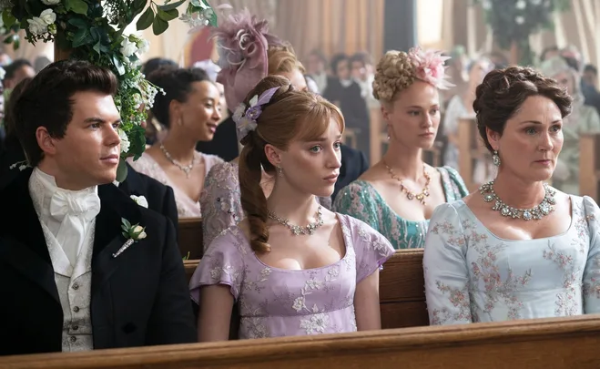Guests at a wedding in Regency era attire in a scene from "Bridgerton," sitting in a church with floral decorations.